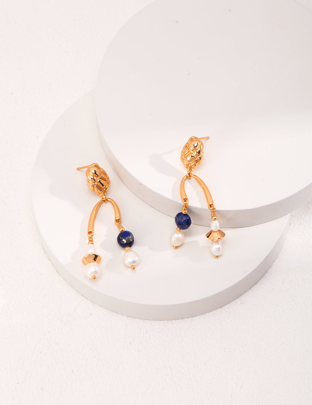  Stunning gold earrings with blue lapis lazuli stones and pearl accents, perfect for adding elegance to any outfit.