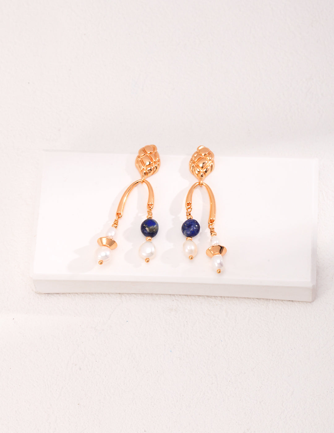 Stunning gold earrings showcasing blue lapis lazuli stones, enhanced with shimmering pearls for a chic accessory.