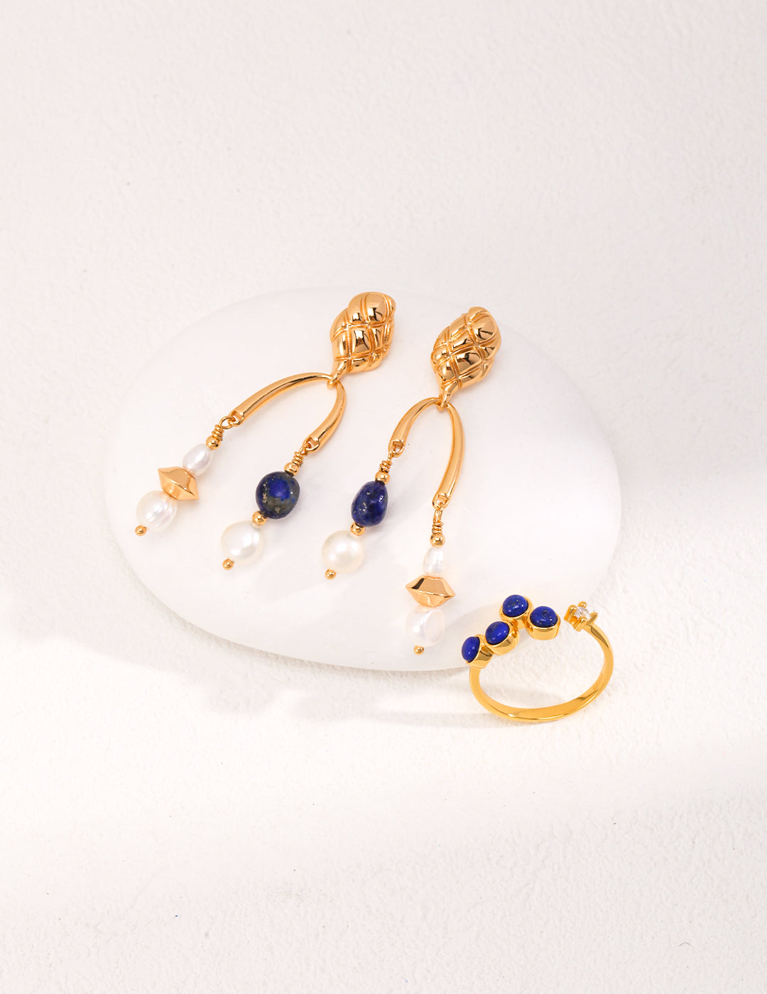 Beautiful gold earrings with blue lapis lazuli stones, alongside a matching ring and pearl details for a cohesive look.