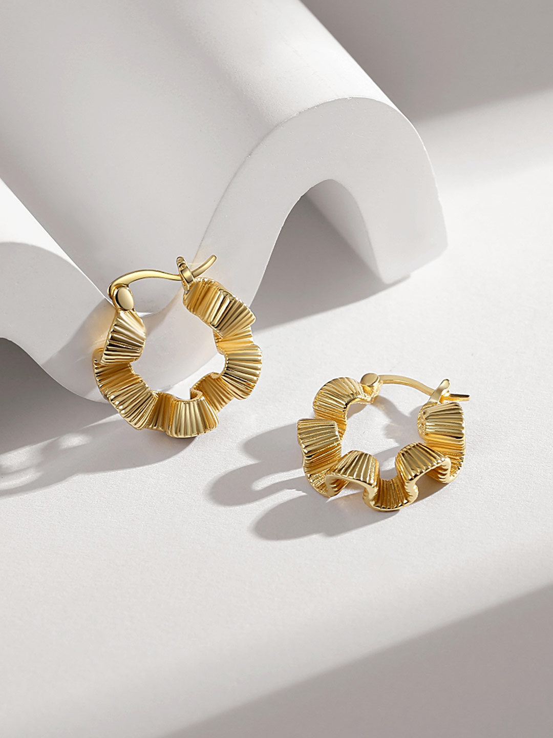 Elegant gold hoops with ruffled edges and detailed creases.