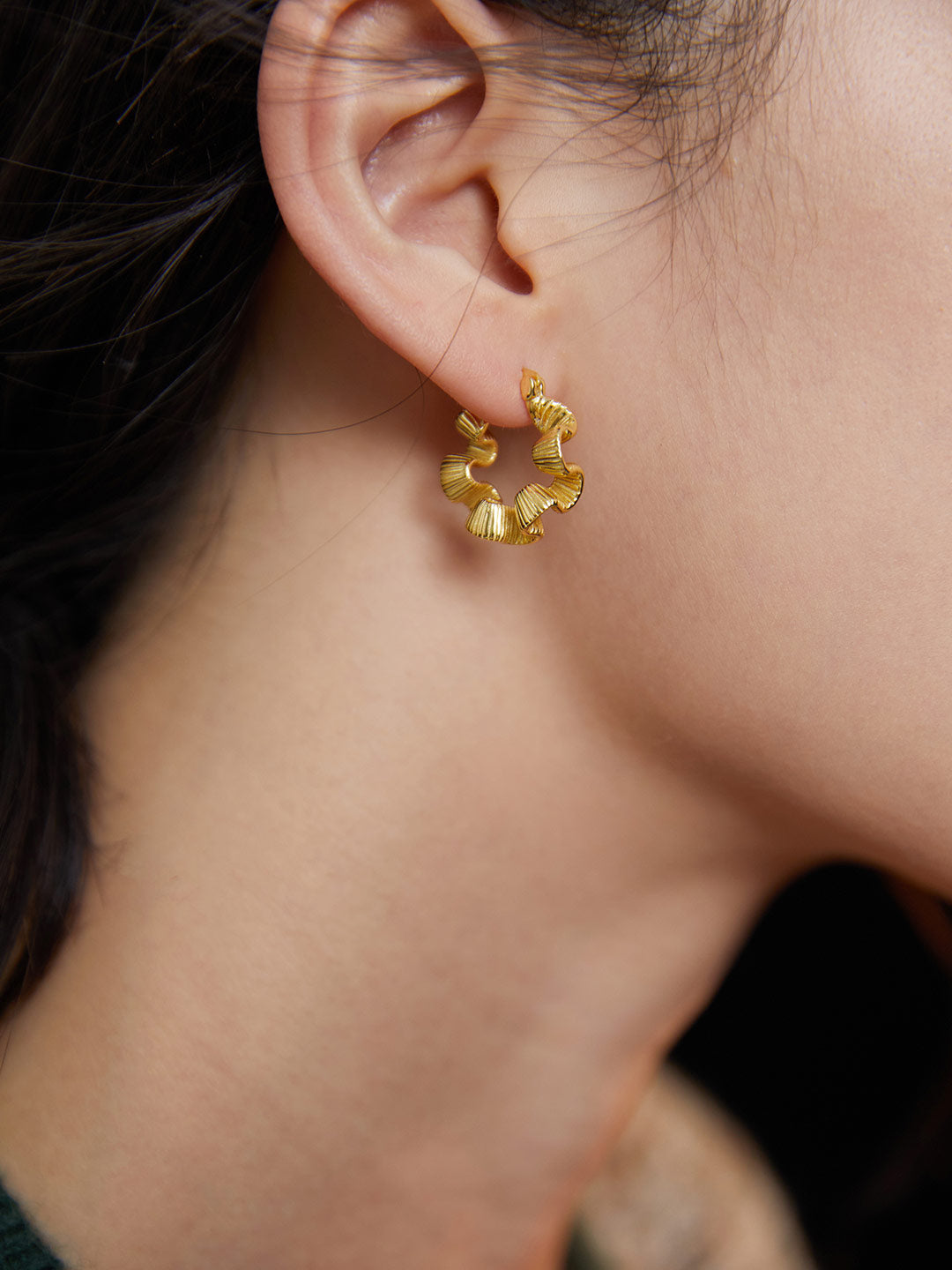 Model showcasing gold earring with visible creases.