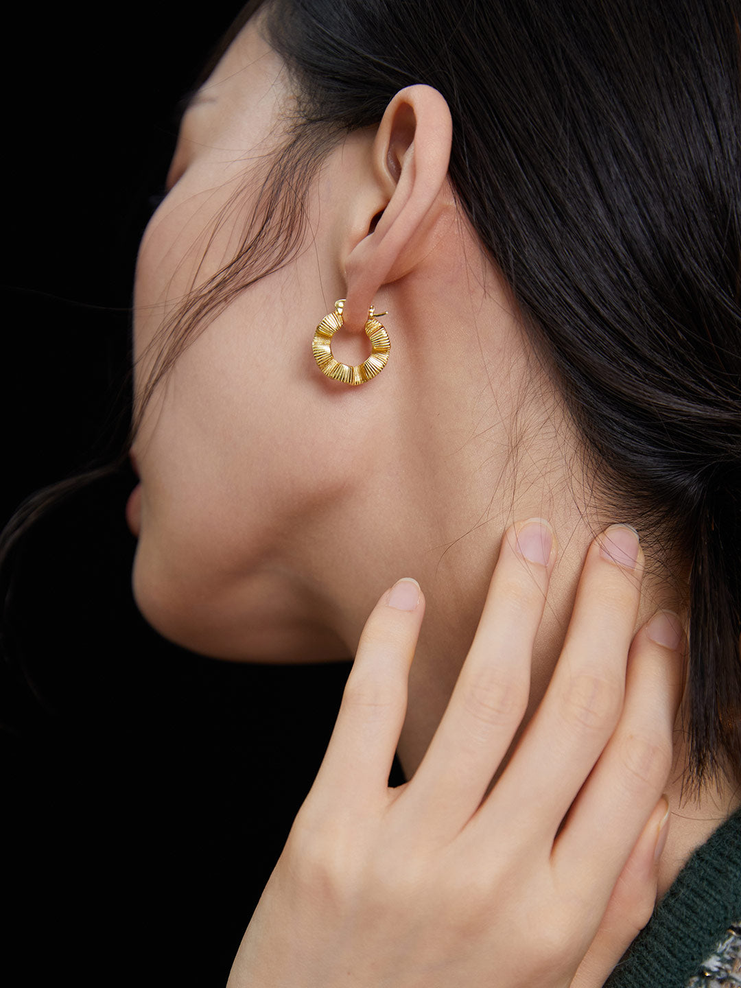 Woman with gold hoop earring featuring small flower design, showcasing intricate creases on the model's earlobe.