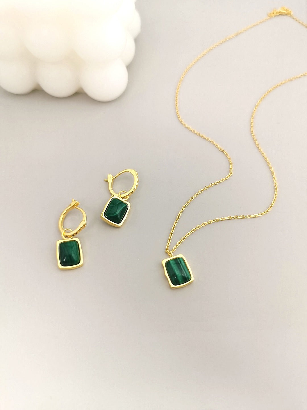 Matching malachite necklace and earrings set, both adorned with green stones.