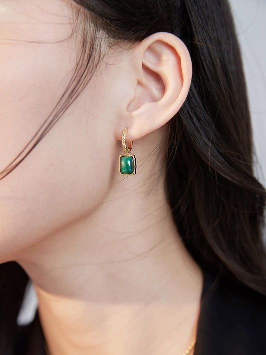 Woman adorned with malachite earrings featuring green stones.