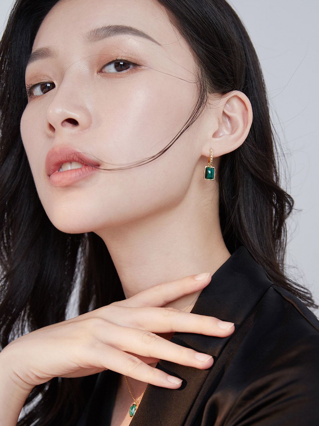 Woman in black dress accessorized with malachite earrings and necklace.