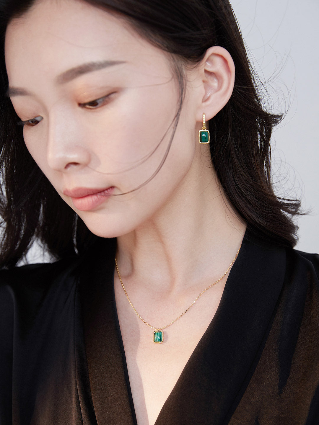  Woman in black dress accessorized with malachite earrings and necklace.