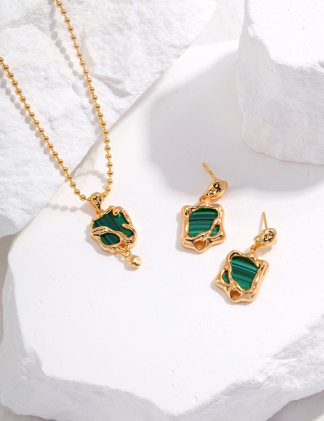 Stunning malachite pendant necklace and earrings on white stone.