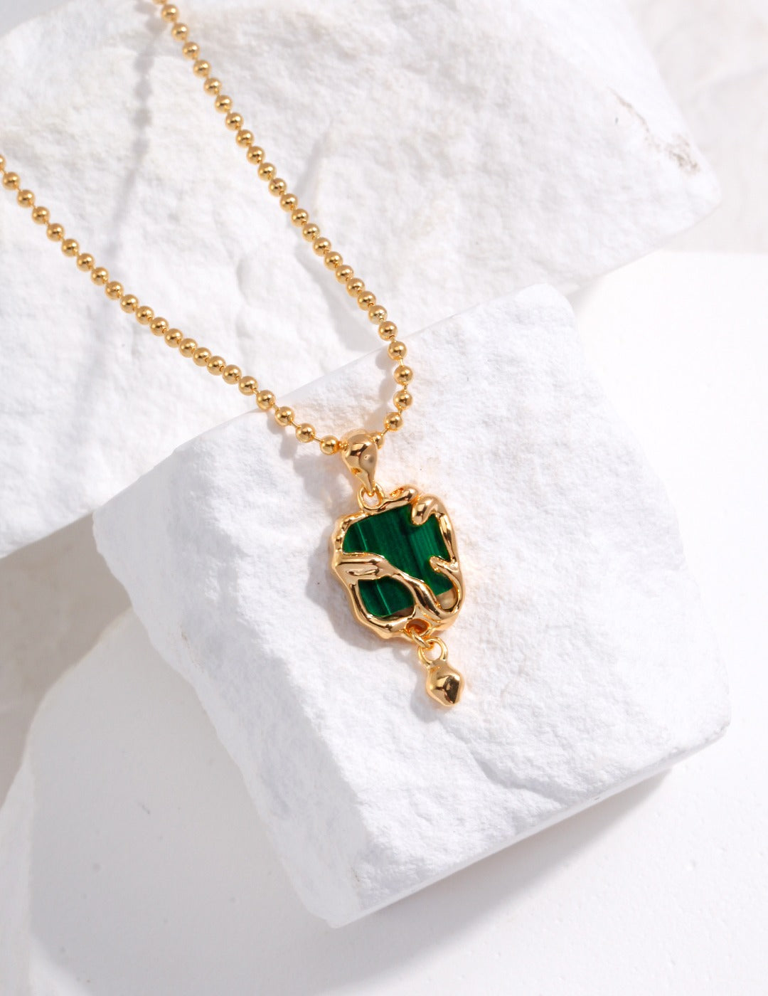 A stunning gold chain necklace with a captivating green malachite pendant.