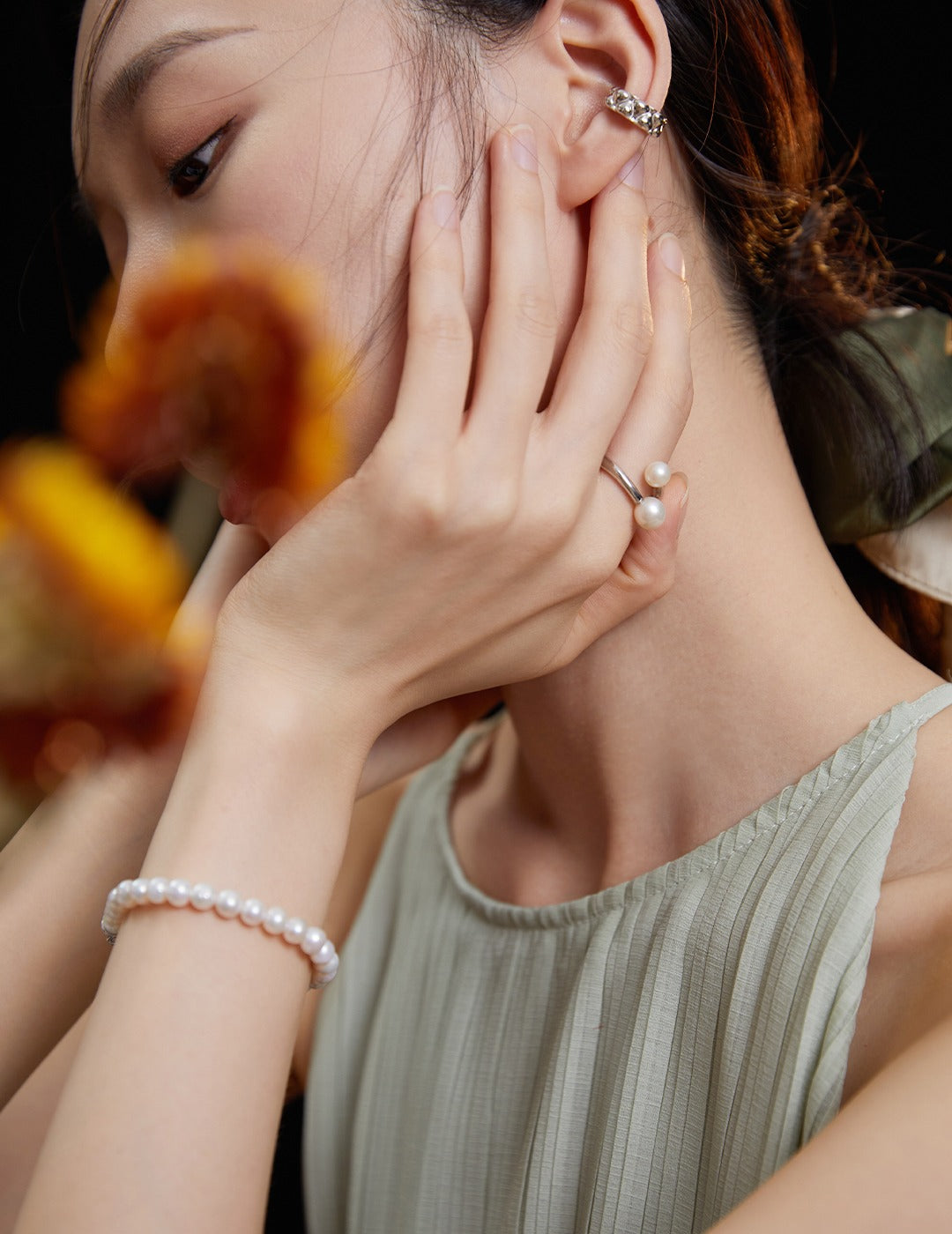 Woman with pearl bracelet and earrings, wearing silver wrap around ring with freshwater pearls.