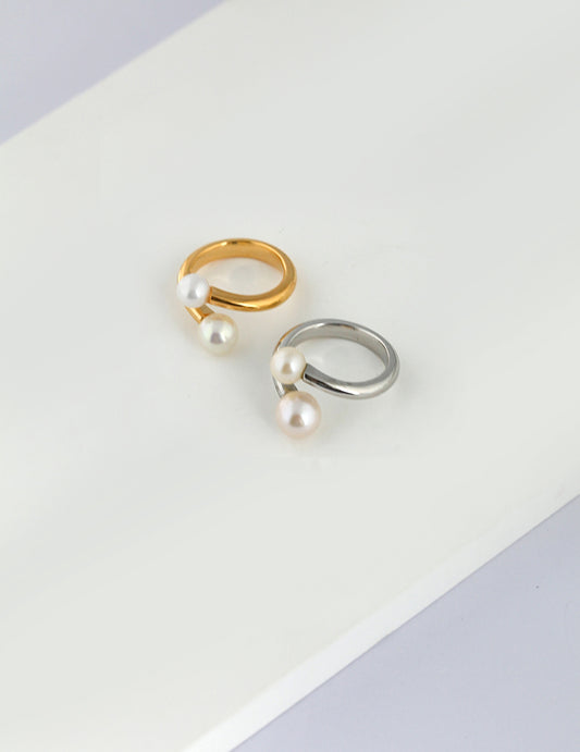 Two elegant rings adorned with lustrous freshwater pearls, encased in silver and gold wraps.