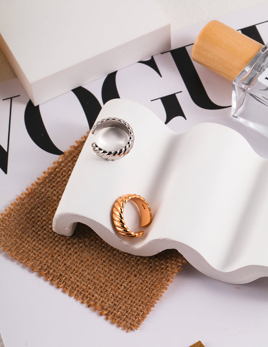 Stylish table decor featuring 2 rings (one silver and one gold), perfume, and magazine.