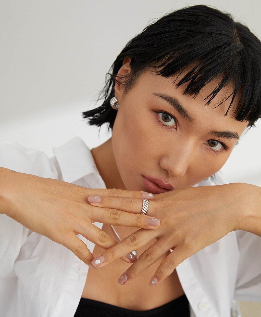 Black-haired woman, accessorized with a silver ring.