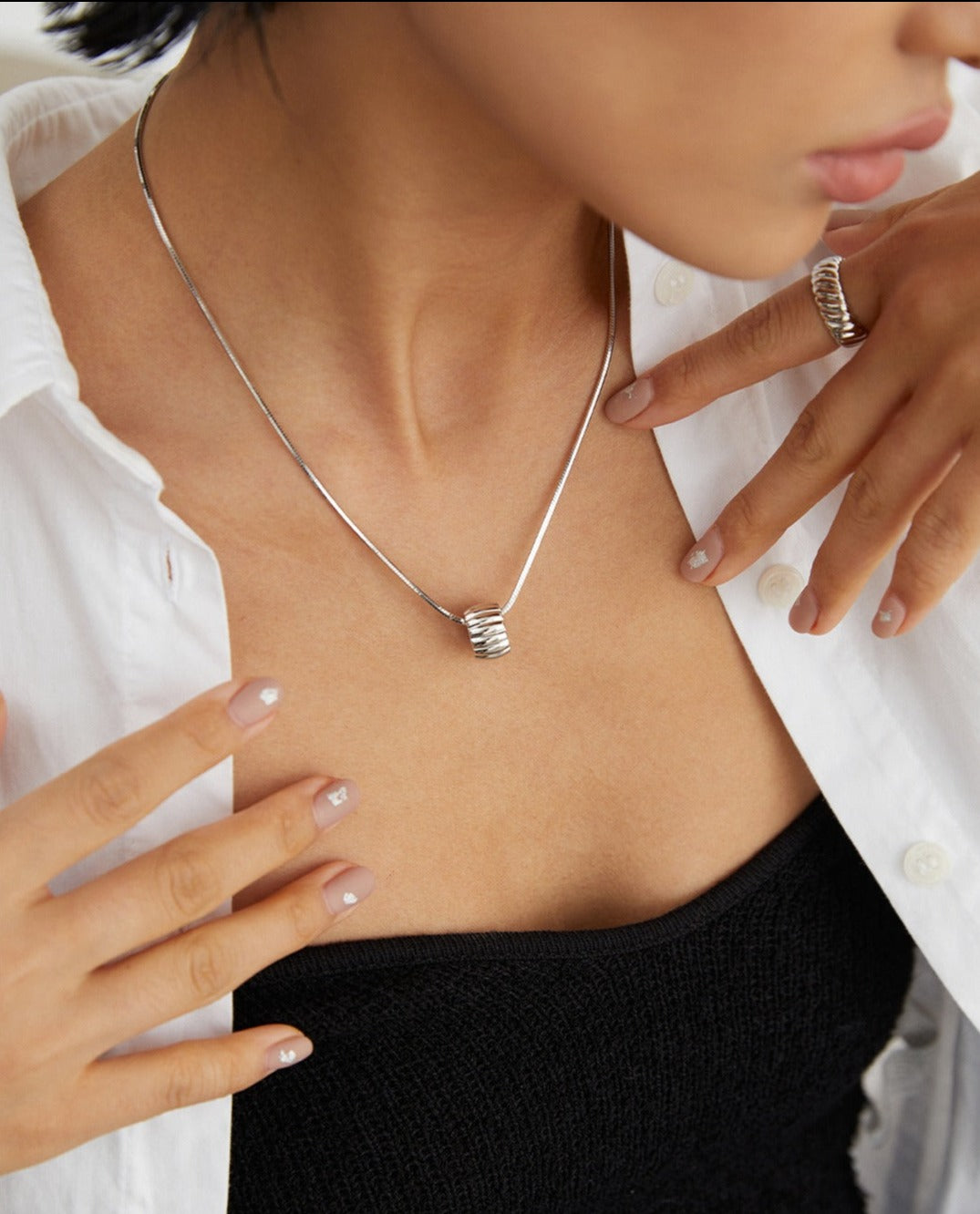 A woman wearing a silver necklace and ring, adding elegance to her attire.