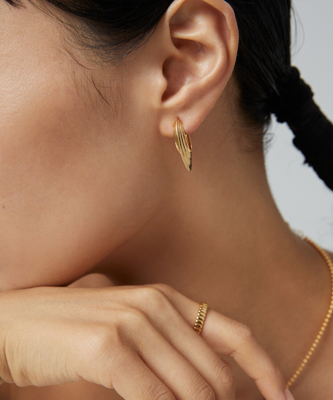 Lady wearing gold disc earrings and chain.