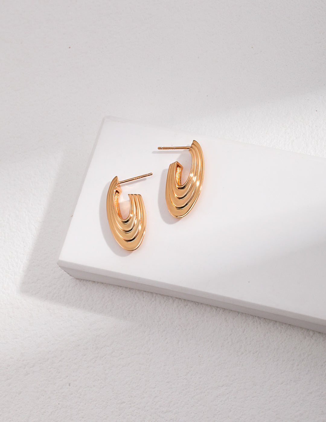 Shiny gold earrings on white background.