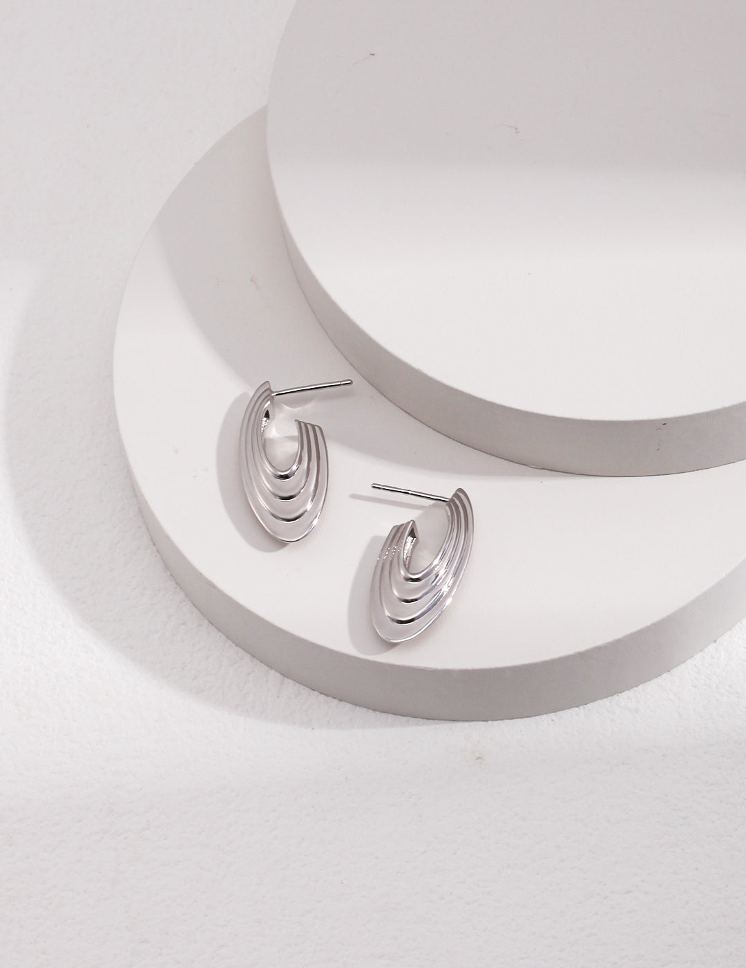 Stylish silver disc earrings on white backdrop.