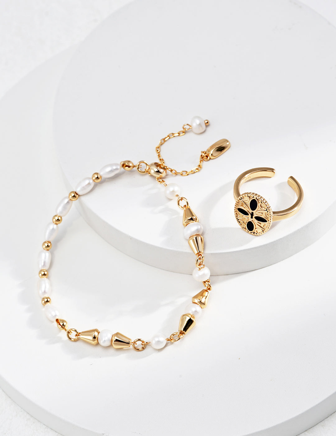 Stylish gold-plated bracelet and ring featuring freshwater pearls on white.