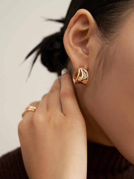 Close up shot of model wearing gold hoop earrings, looking stylish and elegant.