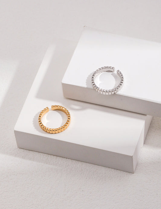 Two ribbed rings, one silver and one gold, placed on top of a white box.