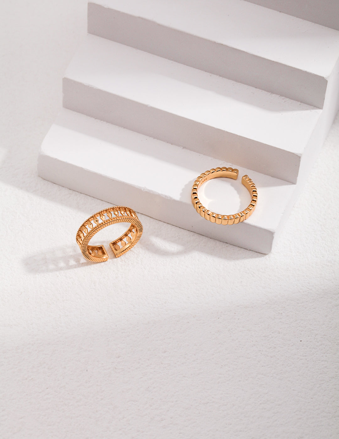 Pair of elegant gold rings on white background.