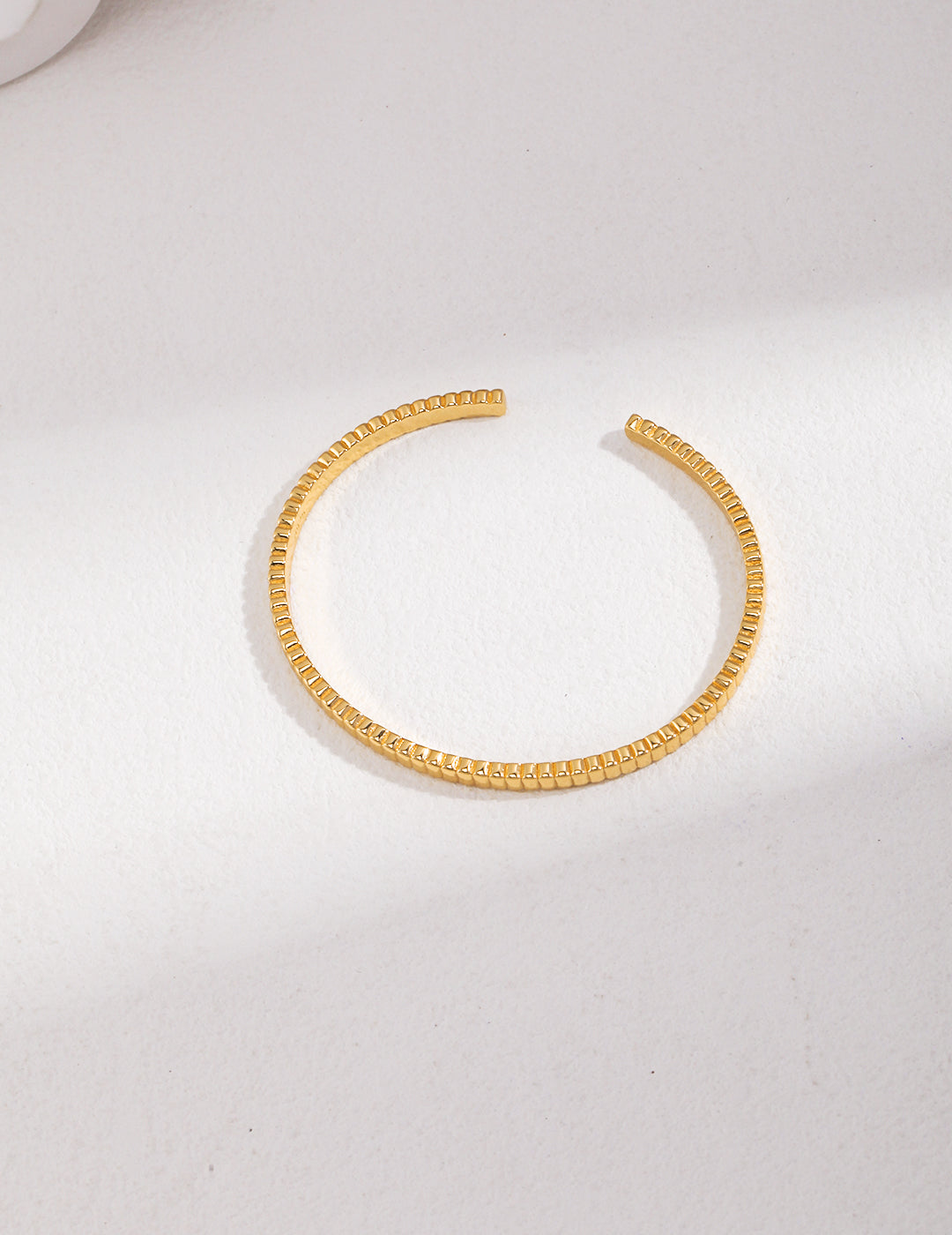 A ribbed gold bangle, adding elegance and sophistication to any outfit.