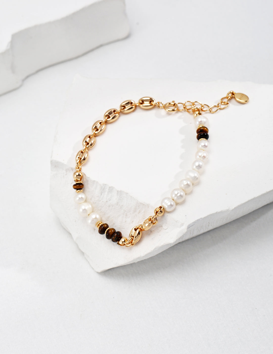 Elegant bracelet in gold and white hues with a pearl accent on a dainty gold chain.