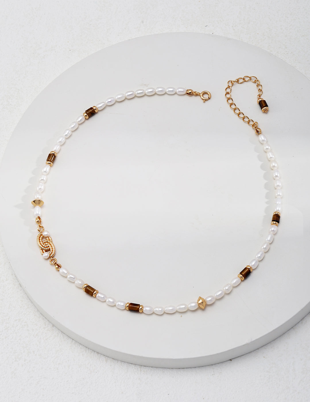 Ethnic style necklace neatly arranged in perfect circle. Necklace is made of pearls, with tiger's eye stones infused in between