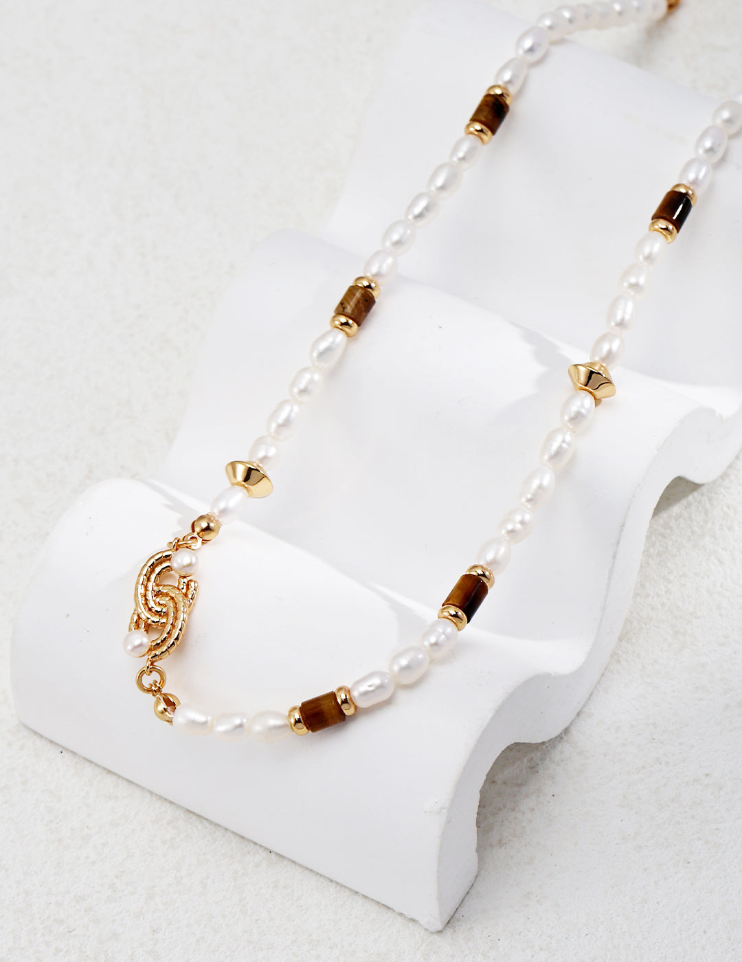 Ethnic style pearl tiger's eye necklace placed on uneven surface