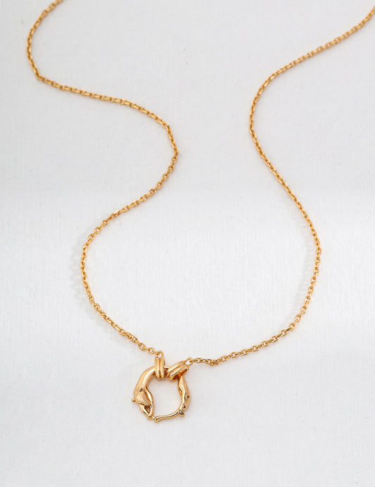 A gold plated necklace with a circular pendant featuring two half foxes linked together.