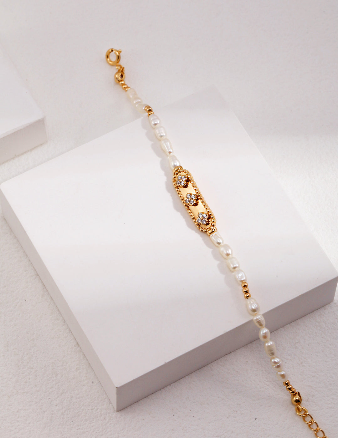 A gold bracelet with clover design, featuring white pearls and zirconia, from Mezuille.
