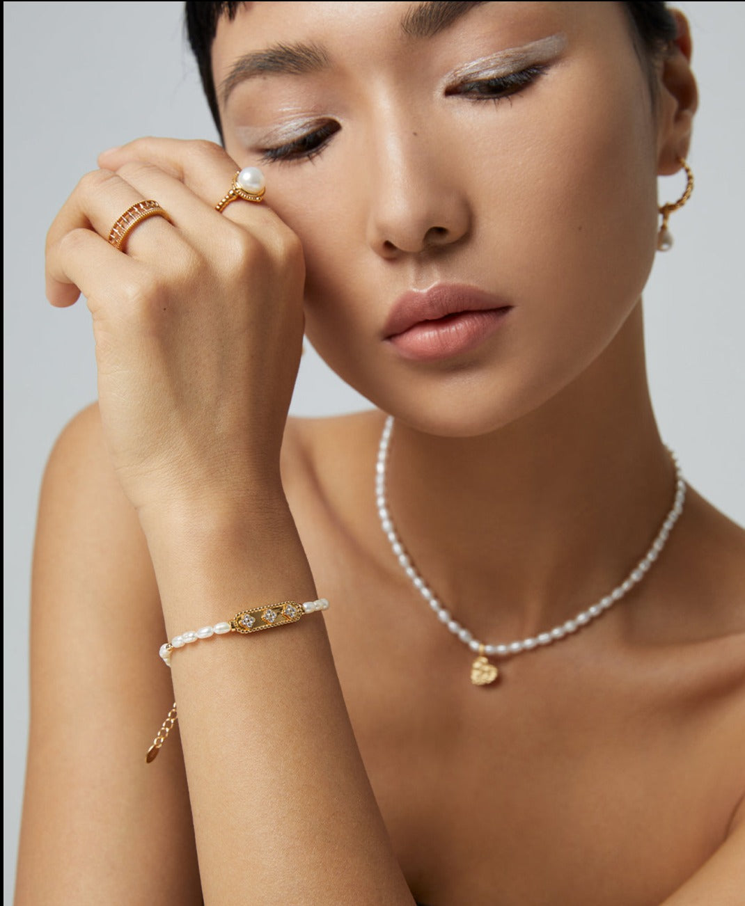 Sophisticated lady wearing a gold bracelet and a pearl necklace.