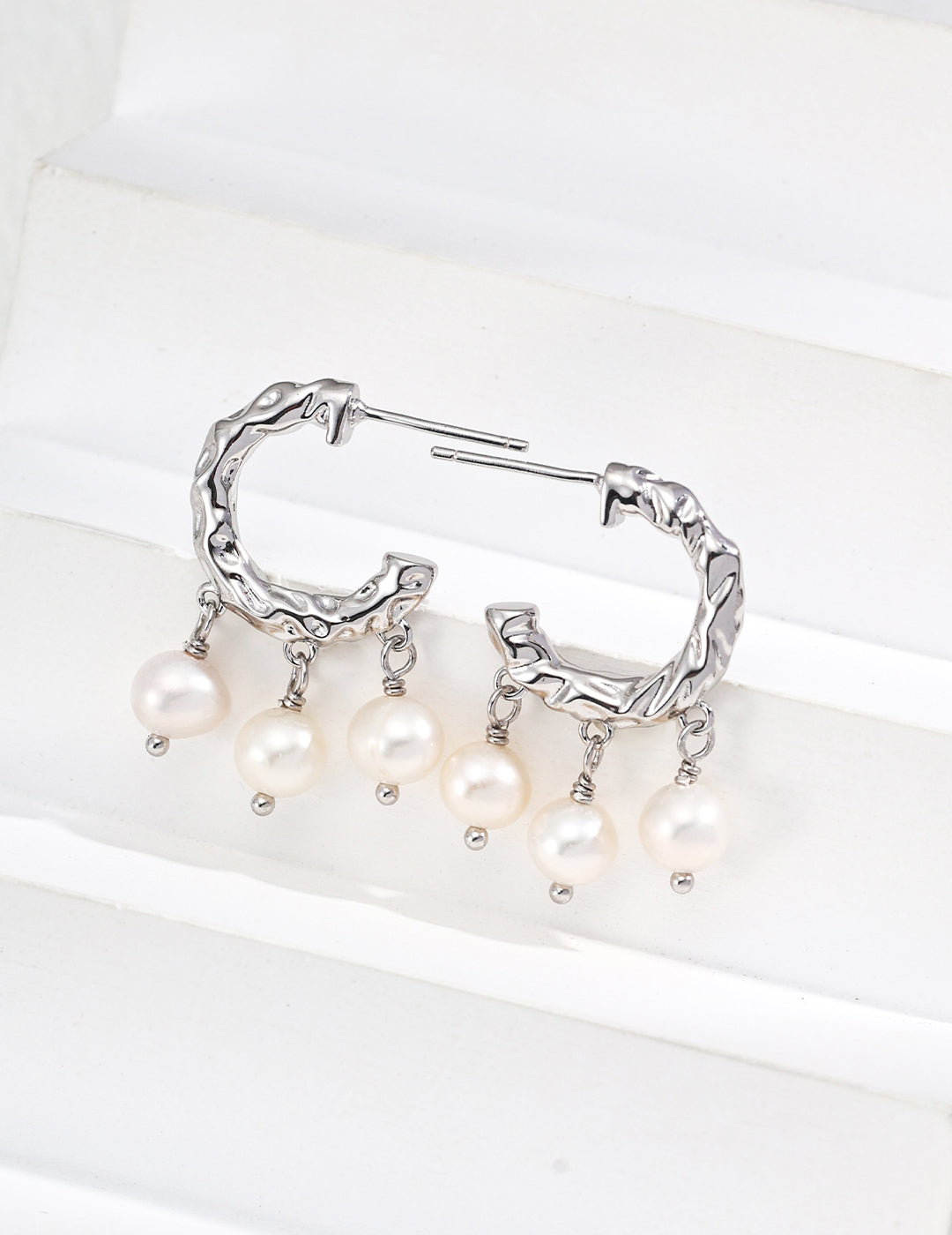 Stunning silver hoop earrings featuring delicate white pearls, ideal for a chic and timeless accessory.