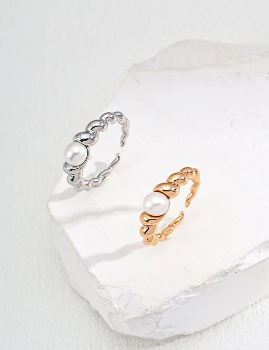 A pair of stylish rings with gold and silver stones resting on a white surface, offered in silver or gold finishes.