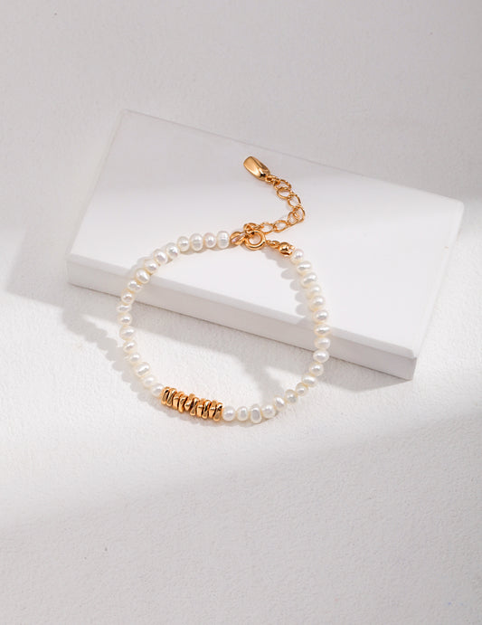 A gold bracelet featuring a pearl charm and a secure gold clasp, showcasing elegance and sophistication.