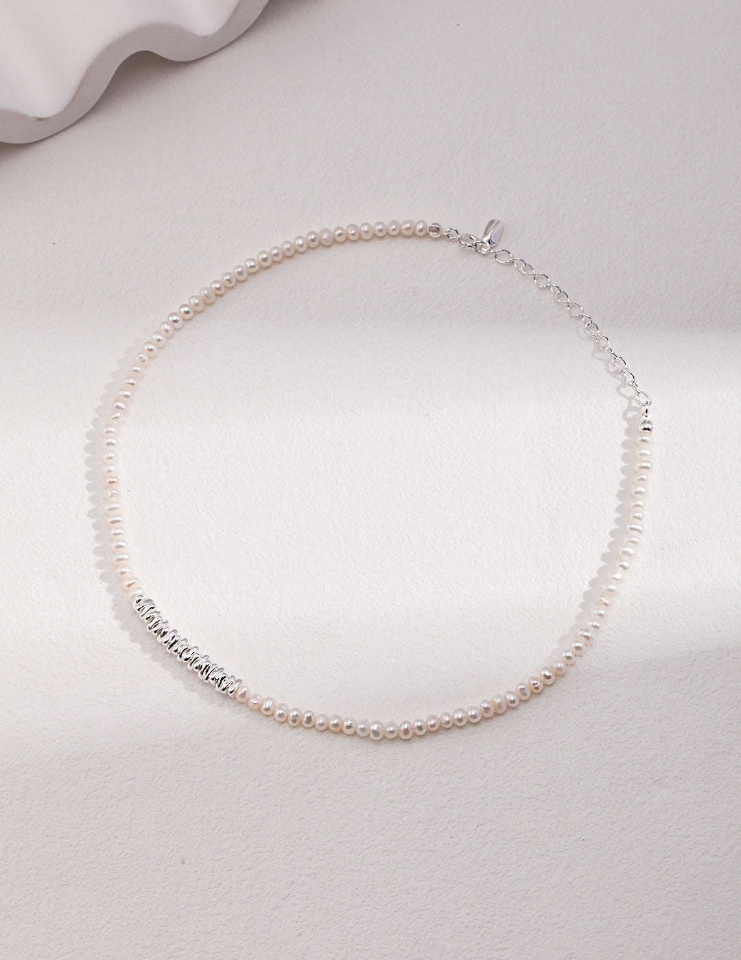 Elegant silver chain necklace adorned with white pearls.