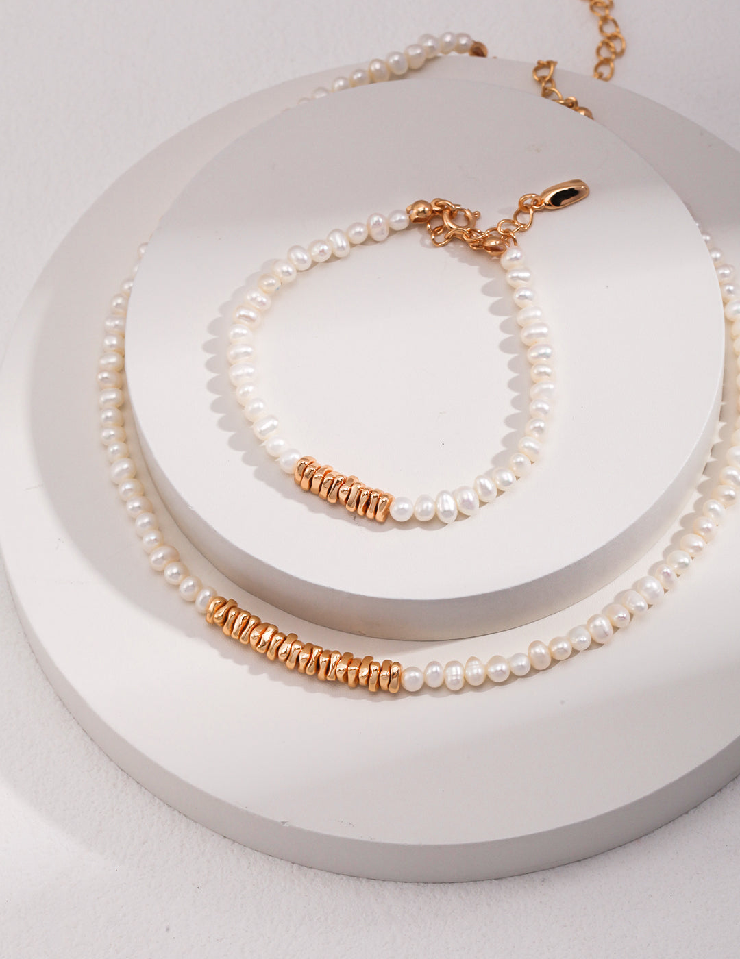 A stunning white pearl necklace and bracelet set on a white plate. Gold and freshwater pearl beads create an elegant and timeless look.