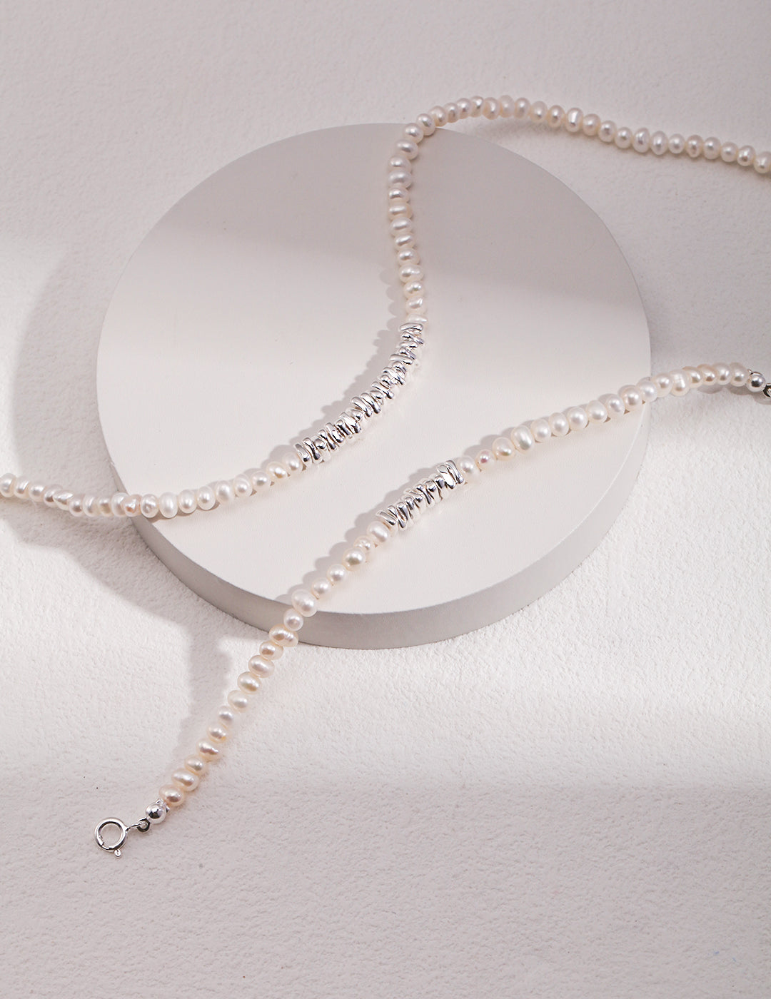 A stunning silver chain necklace adorned with white pearls, featuring silver and freshwater pearl beads. Includes a matching bracelet.