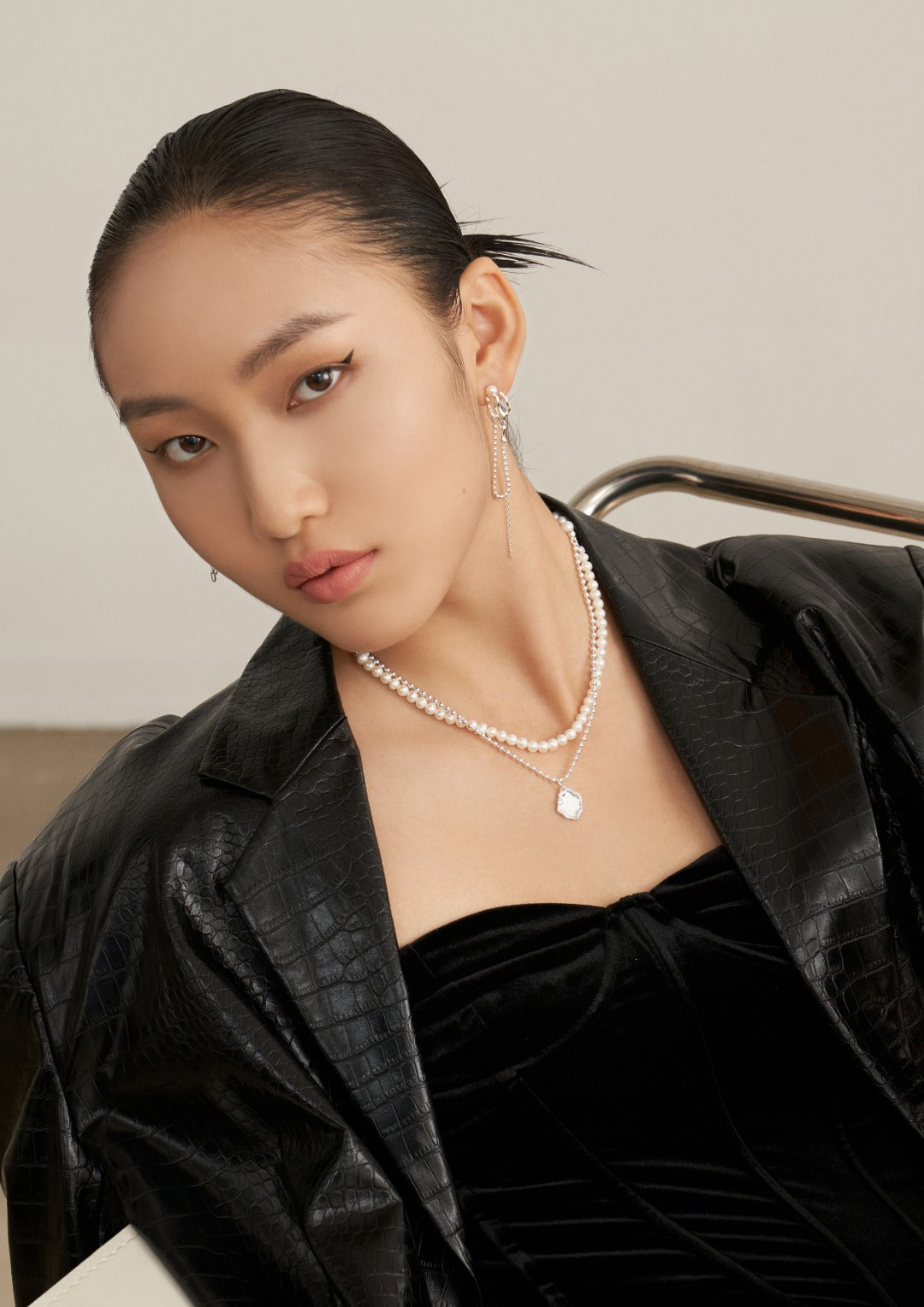 Fashionable woman donning a black dress and a silver necklace featuring freshwater pearls.