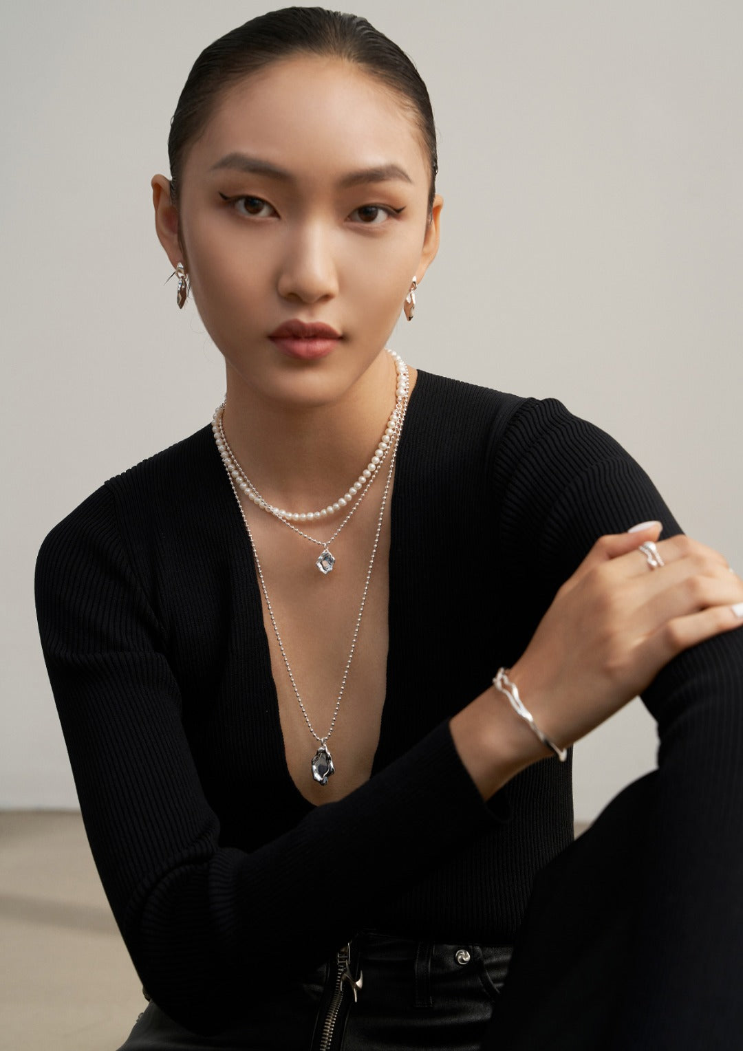 A woman in a black sweater wearing a silver necklace adorned with freshwater pearls.