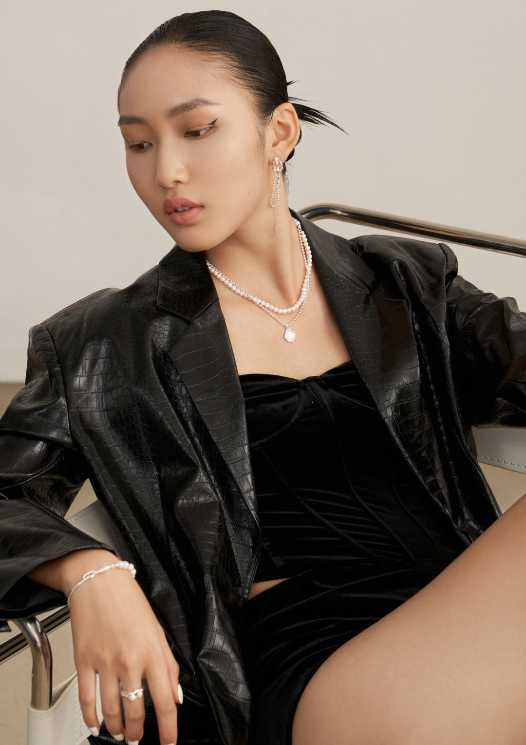 A chic woman in a black leather jacket and high heels, donning a silver necklace embellished with freshwater pearls and accessorized with jewelry from the same line.