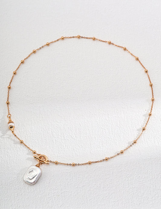 Elegant gold chain bracelet with dotted charms, showcasing square freshwater pearl pendant on chain.