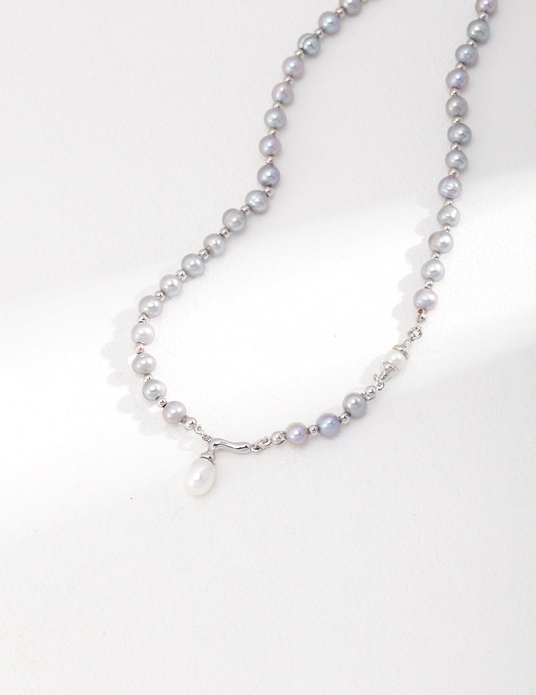 A silver necklace with a grey freshwater pearl pendant on a delicate chain.