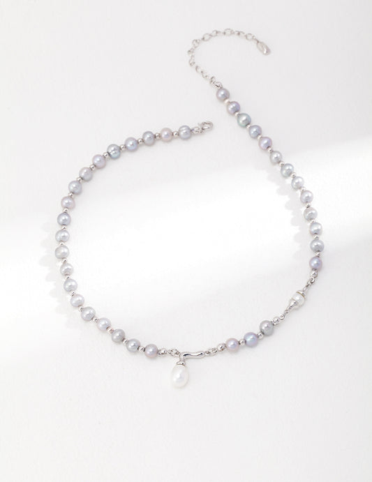 A silver necklace with a delicate pearl pendant, showcasing grey freshwater pearls.