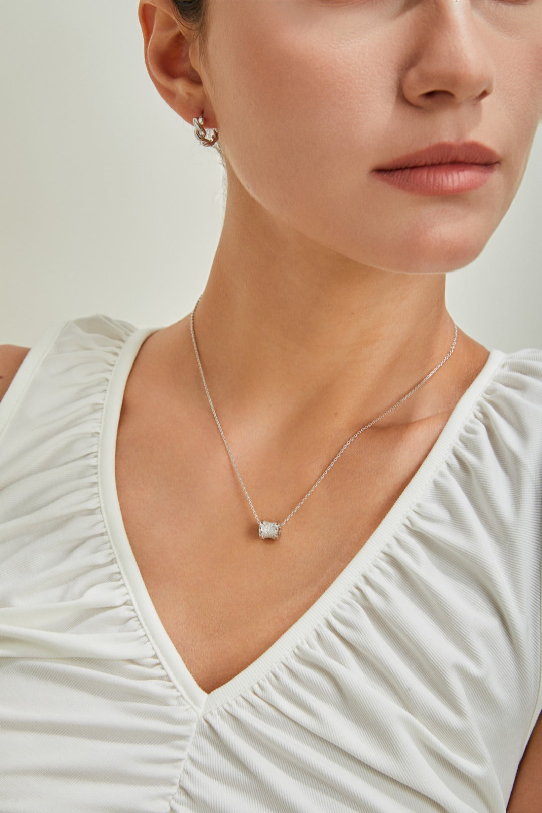 A woman wearing a white top and a necklace, radiating sophistication and grace in her appearance.