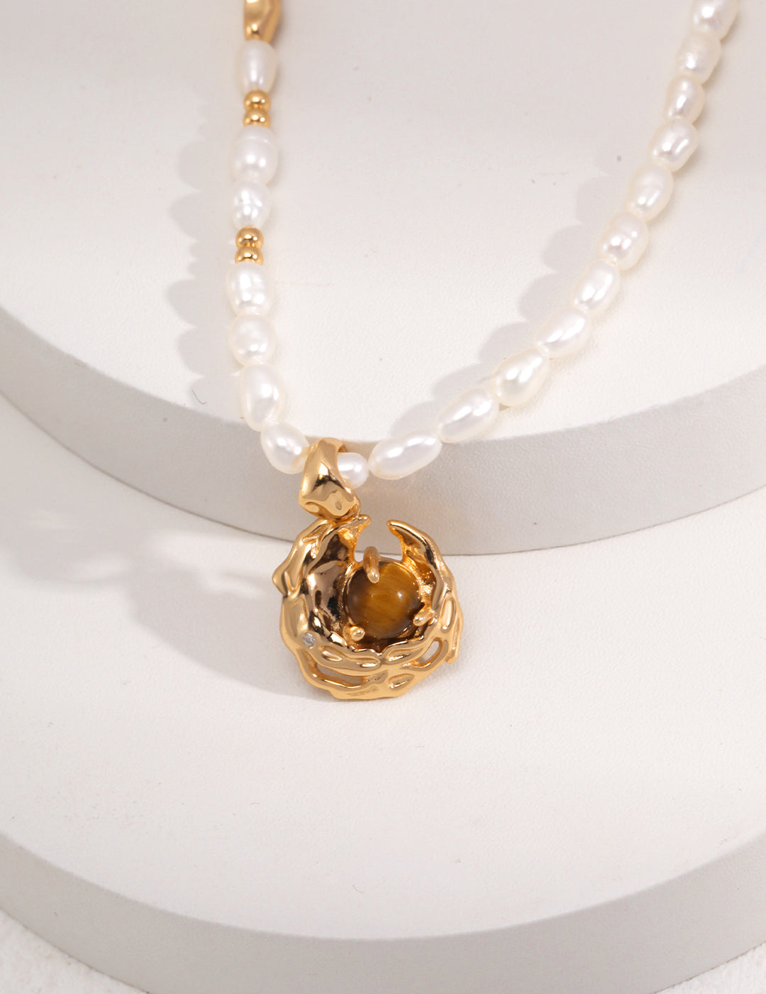 An exquisite gold necklace with pearls, highlighted by a close-up of a rare tiger's eye crescent moon pendant.