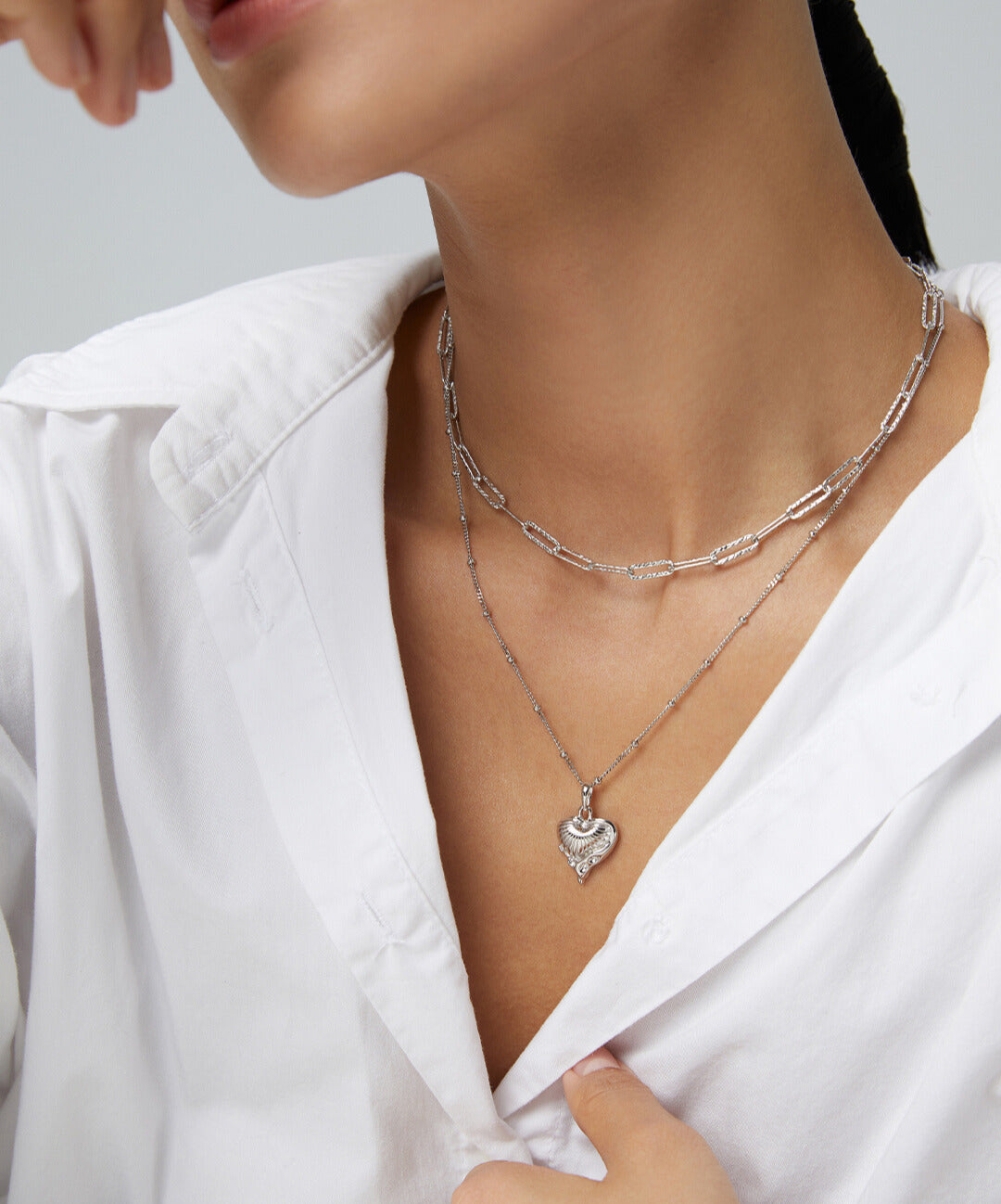  Lady donning white shirt paired with silver chain heart necklace.