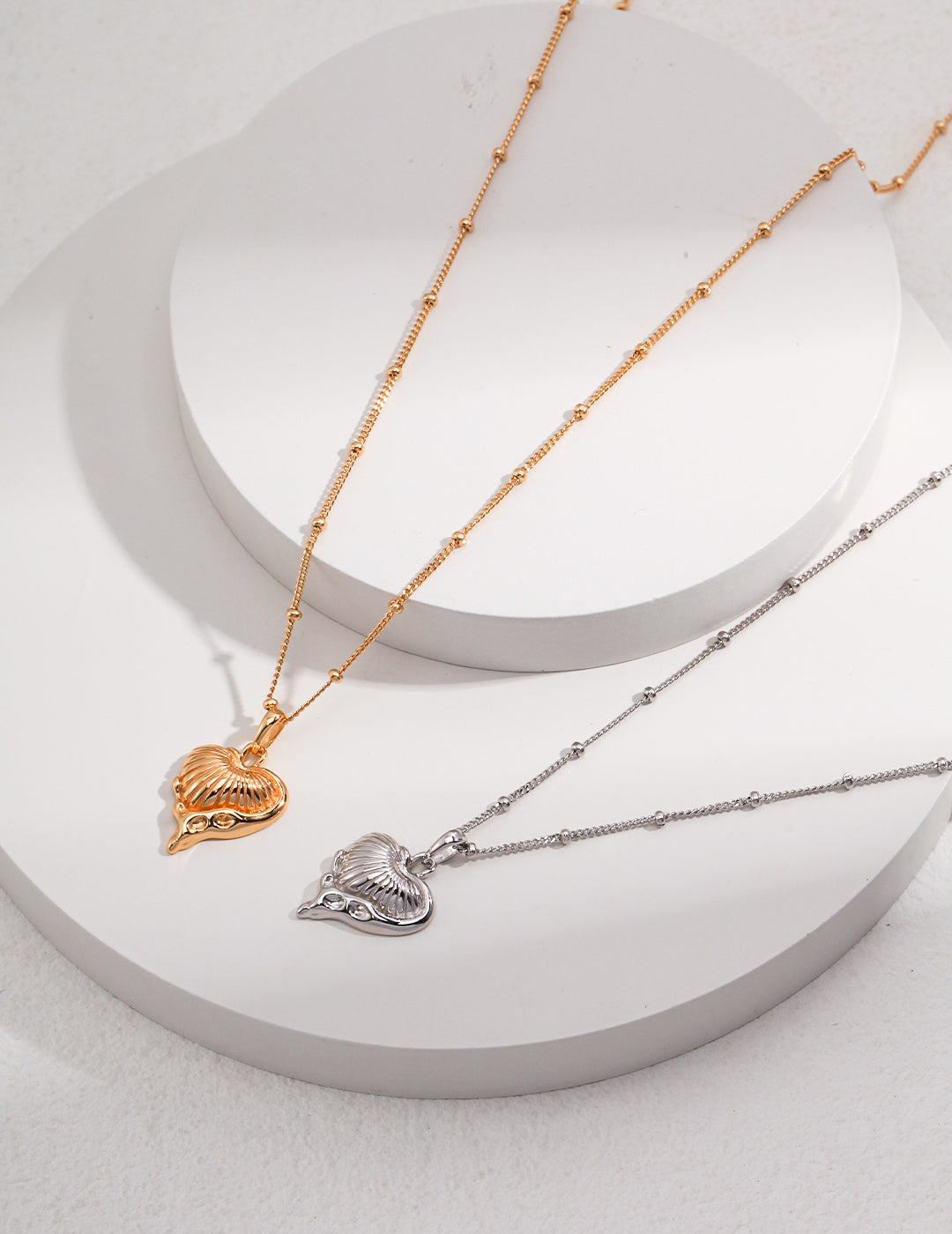 Pair of necklaces featuring heart charms in silver and gold.