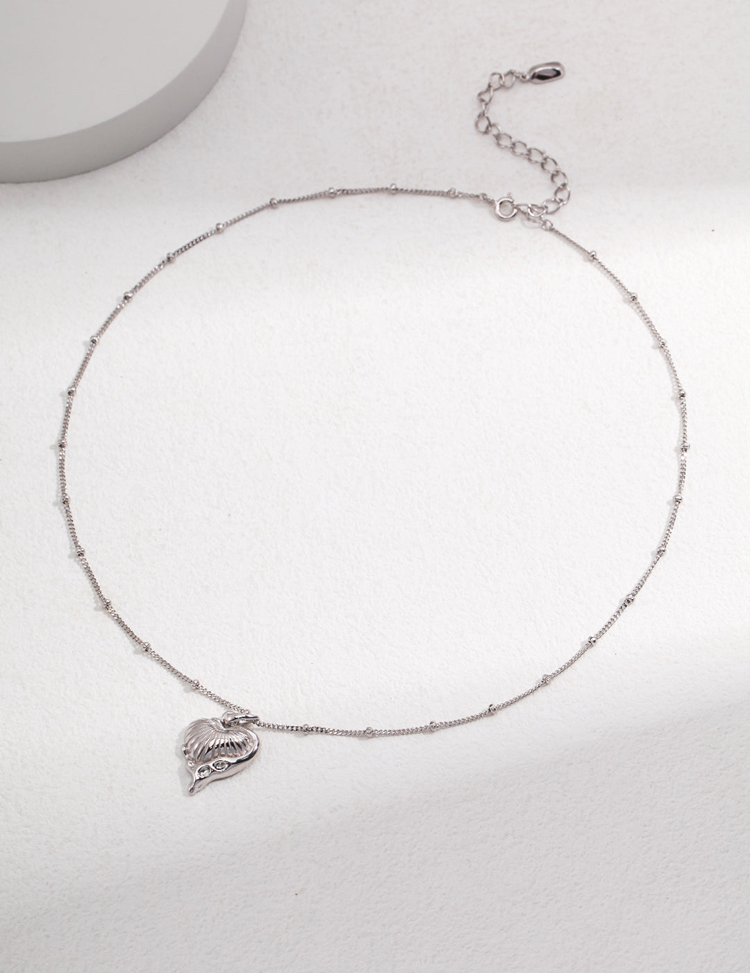 A silver chain necklace with a heart charm hanging from it, adding a touch of elegance and love.