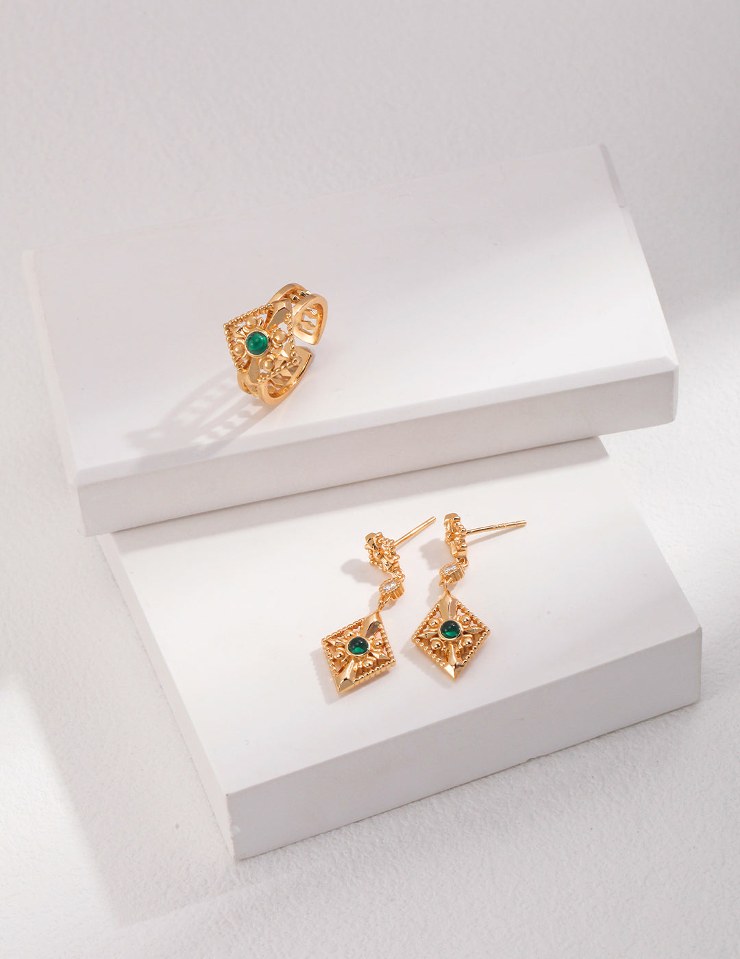 Gold earrings with zirconia stones perched on top, presented with a stylish ring for a complete jewelry look.