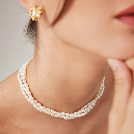A woman in a triple layer rice pearl necklace and earrings, highlighting her refined and elegant look.